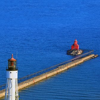 A red lighthouse at the end of a pier.