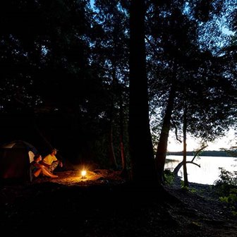 A couple sitting around a campfire at dusk