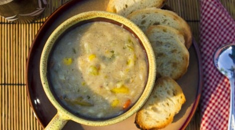 Bowl of clam chowder with slices of bread.