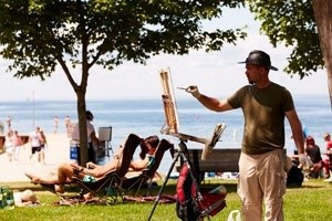 Man painting in a park at the lakefront.