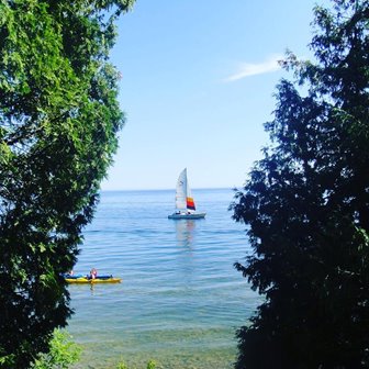 Looking at a sailboat and kayaker peaking out from the trees on the lake