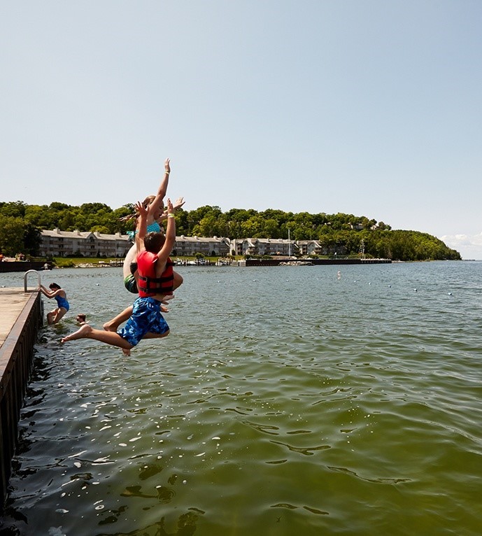 Kids jumping off a dock into the water.