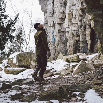 A man looking up at cliffs in the snow.