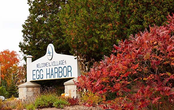 A sign that says Egg Harbor next to bushes