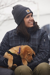 A woman in a beanie holding a dog.