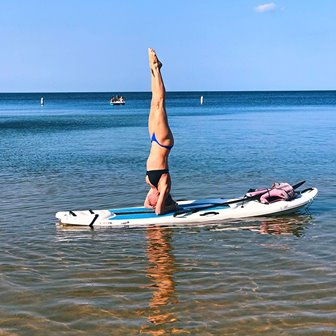 A woman doing a handstand on a paddleboard.