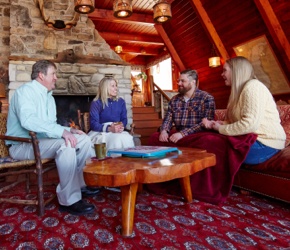 Two couples sitting in a cabin talking.