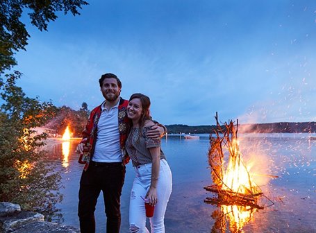 Couple in front of a bonfire at the lake.