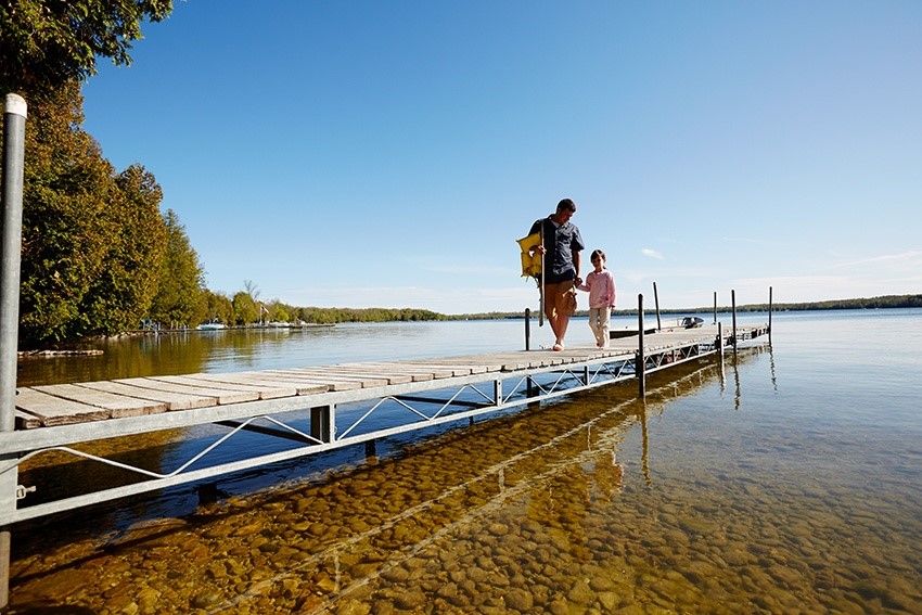 A man and a child walking down a dock after fishing.