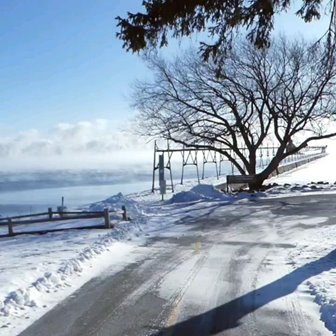 A snowy road leading to a snow-covered pier.