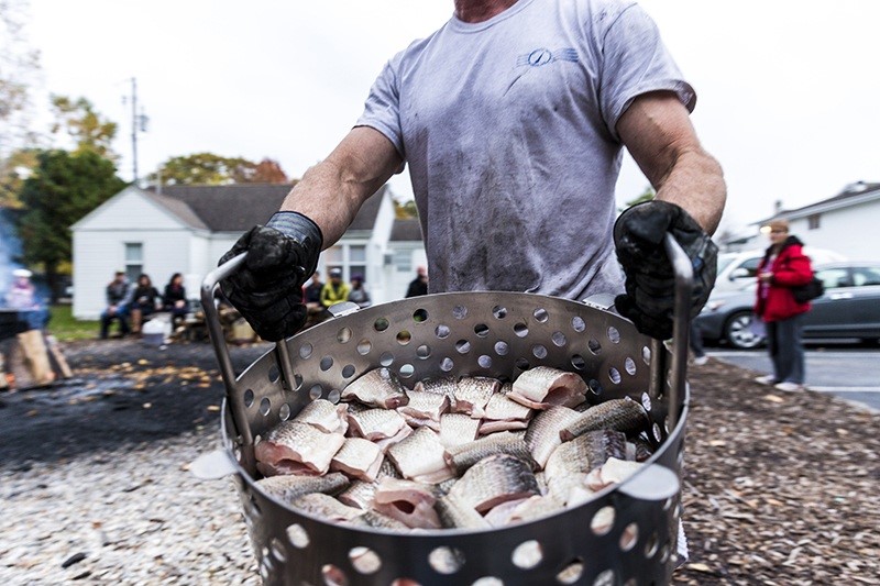 A man holding a fish boil basket full of fish.