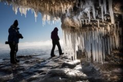 People walking just outside an ice-filled cave