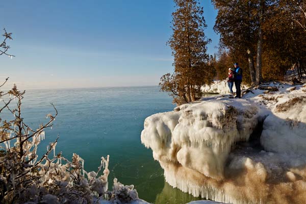 A couple stands atop Cave Point during deep winter.