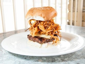 Large burger with crispy onions on a plate