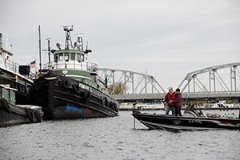 Two people fishing off a boat in a marina