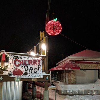 A giant cherry made of lights with a sign that says Cherry Drop in front.