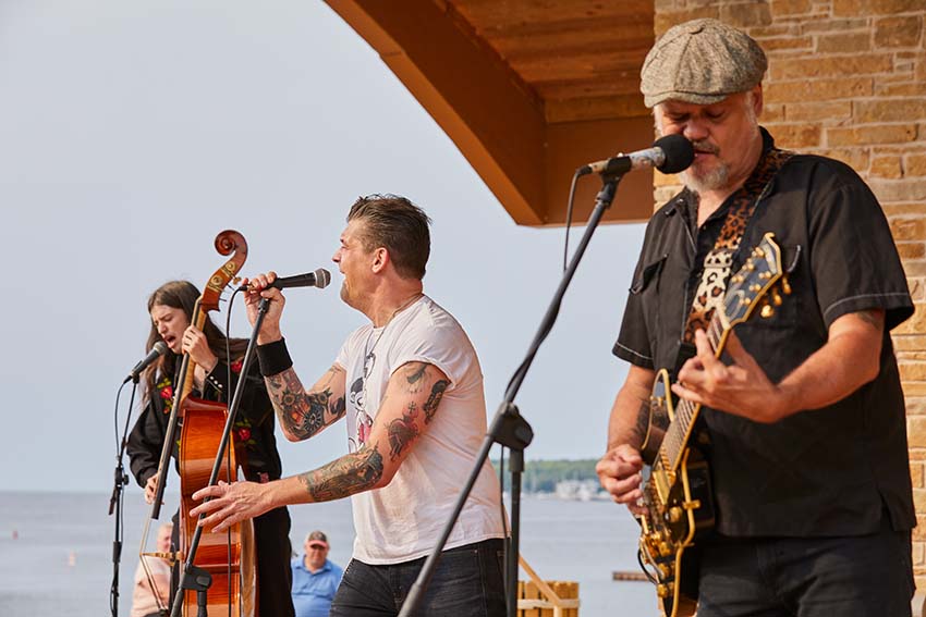 A rock band plays on an outdoor stage aside Lake Michigan.
