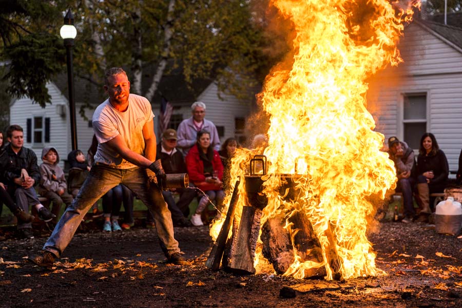 A man tames a giant fire engulfing a basket of cooking fish.