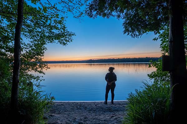 A person silhouetted by the sunset over the lake 