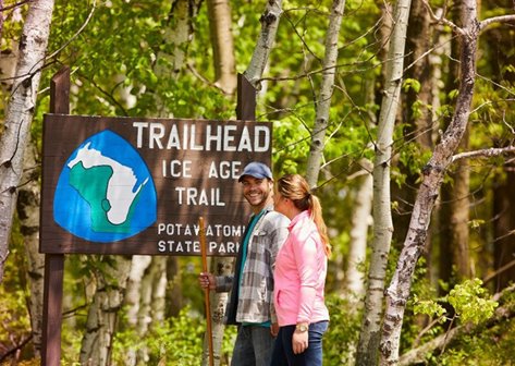 Couple standing in front of the Ice Age Trail trailhead sign.