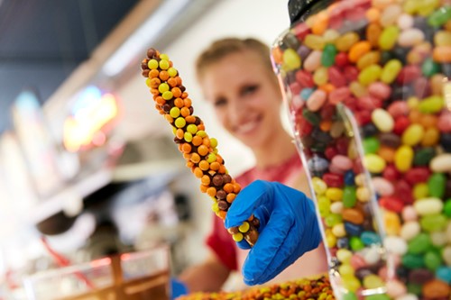 A worker at a candy shop shows off colorful chocolate and jelly beans.