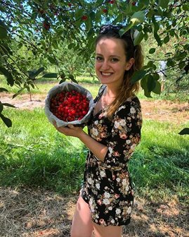 A woman holding up a bucket of cherries.