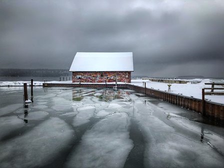 Graffiti-covered building on a snow-covered pier next to the icy lake