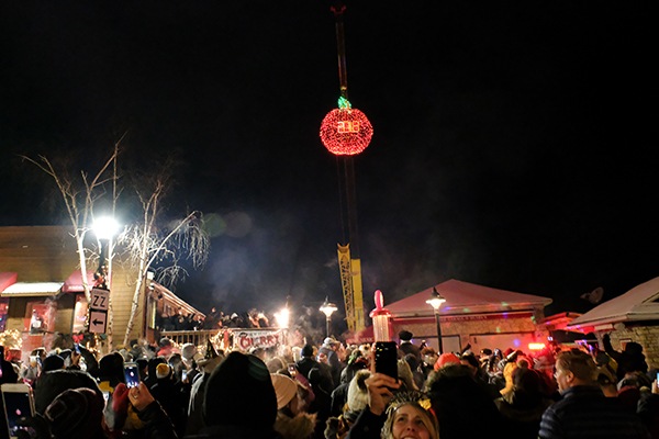 A giant, lit-up cherry hangs above a crows at a New Year's celebration