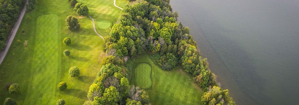A golf course at the lakefront from above.
