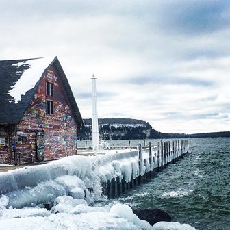A graffiti-covered building on an ice-covered dock.