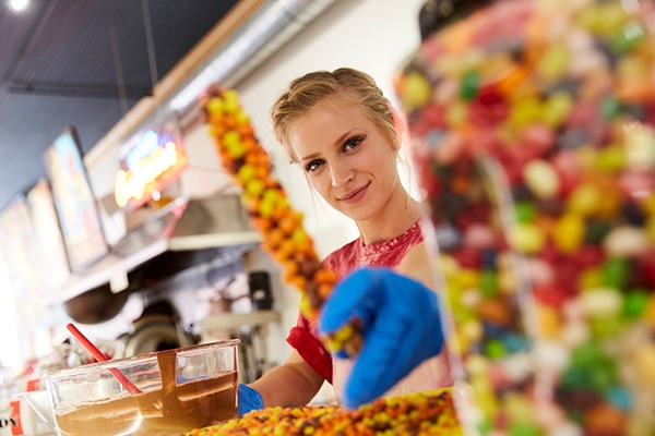 A candy-shop worker presents colorful candies and snacks.