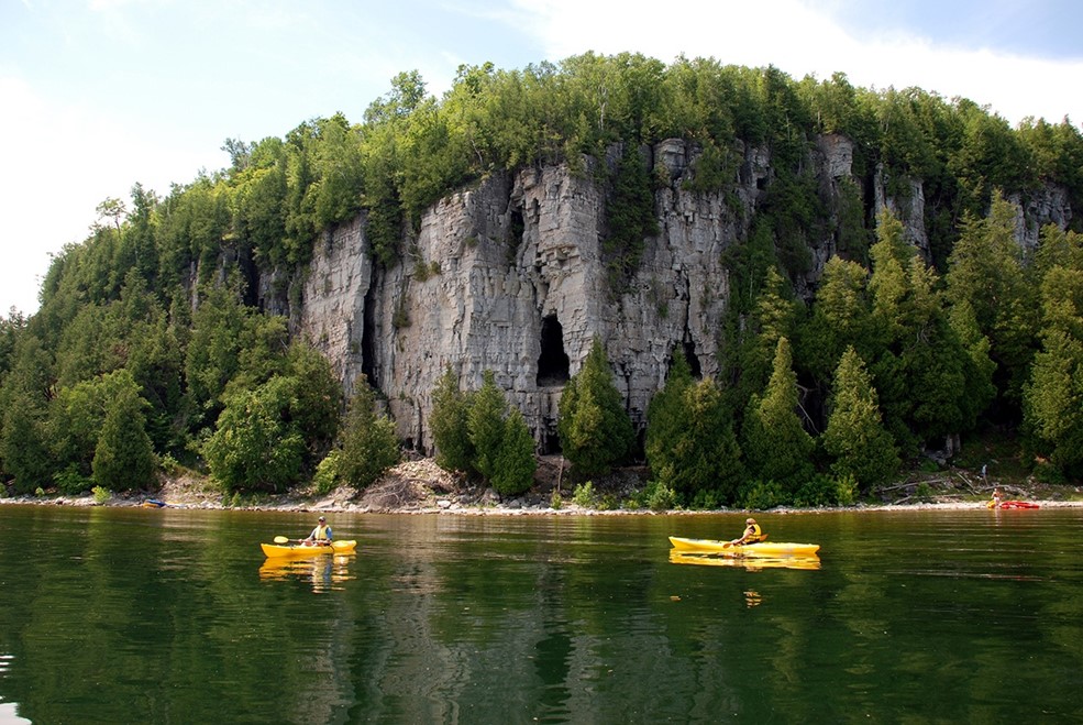 Kayakers paddling beneath and escarpment.