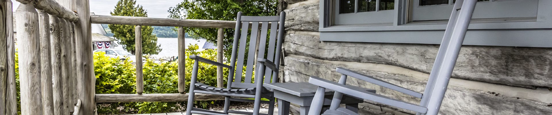 An old rocking chair sits on an outdoor porch on a summer day.