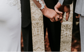 Closeup of bride and groom holding hands.