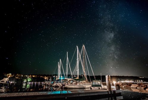 Docked sailboats in a marina against a starry night sky