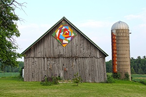 A barn with a colorful wooden barn quilt mural on it