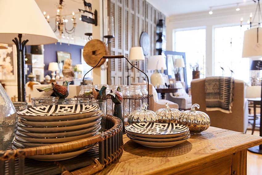 A shot of a high-end furnishing store featuring artsy plates, wooden furniture, and other decor.