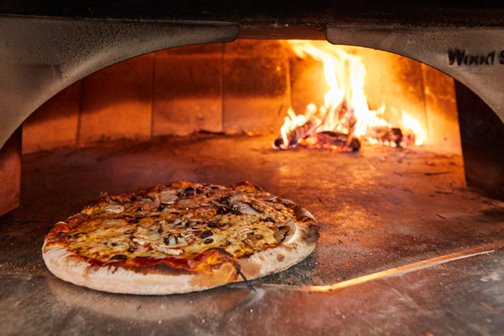 Pizza being cooked in a stone oven.