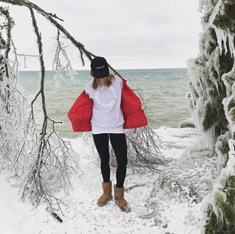 A woman standing between ice-covered trees in front of the lake.