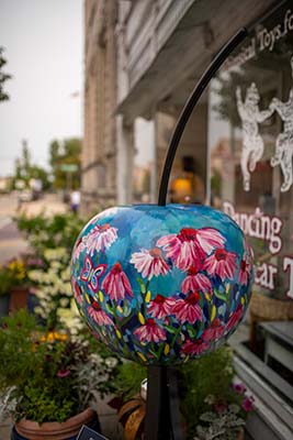 A beautifully painted cherry statue outside a downtown gallery.