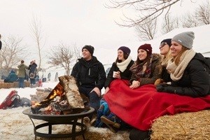 People around a fire under a blanket.