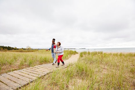 A couple walking on a boardwalk surrounded by grassland