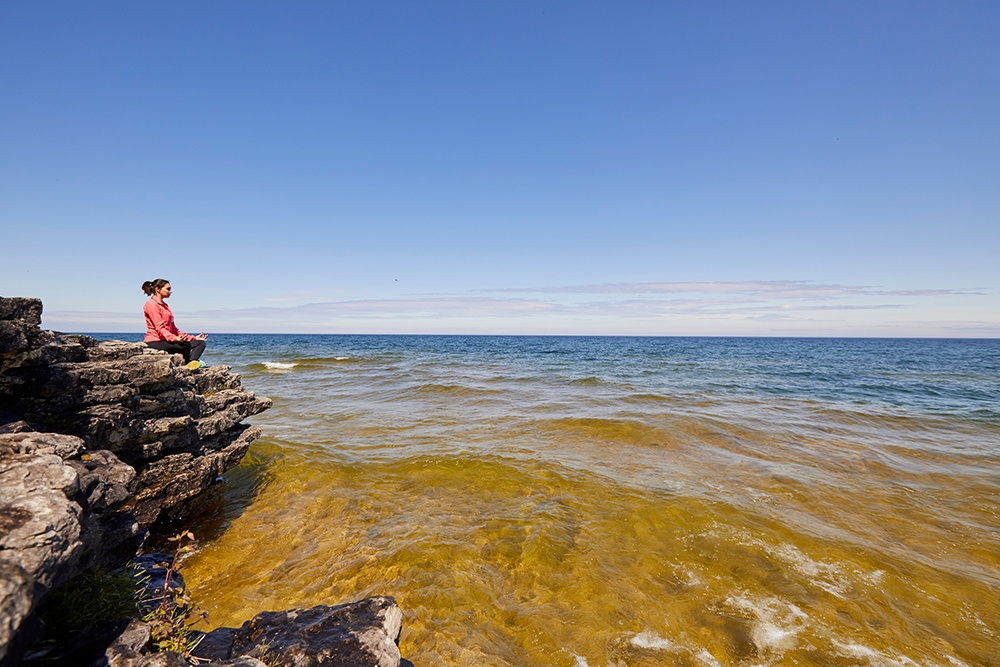Woman sitting on stone looking out over the water