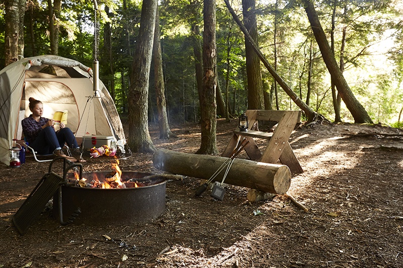 A camper sits in her tent at a remote campsite.