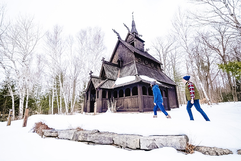 Two people walking toward a wooden building in the snow