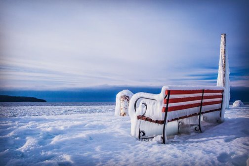 An iced-over bench near the frozen lake