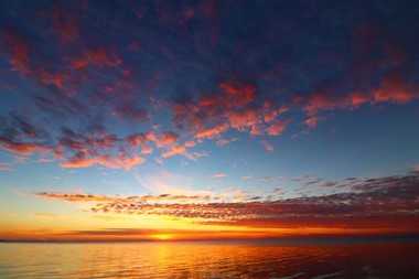 A vibrant, rainbow-colored sunset over a bay in Lake Michigan.