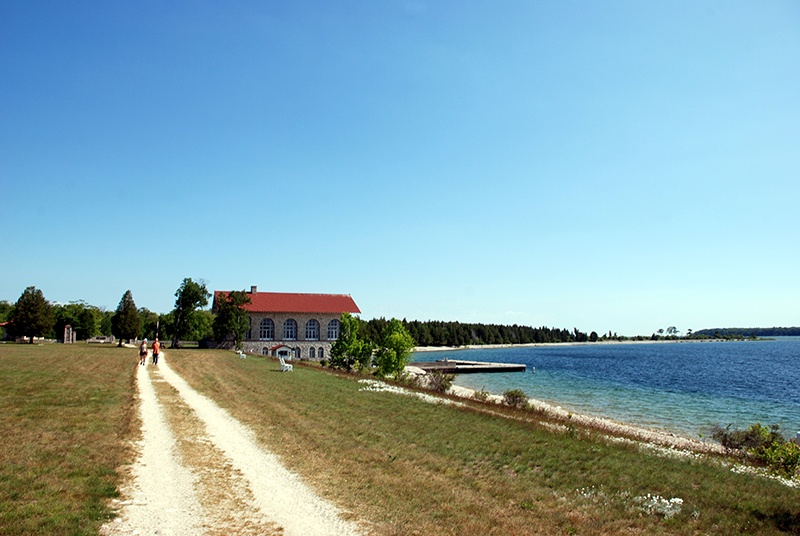 Unpaved road near water leading to a building with a red rood