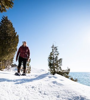 A woman snowshoeing above the lake.