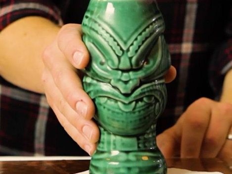 Hands holding a tiki drink glass